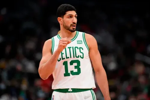 لاعب كرة السلة خامان مالواش يرتدي زي فريق بوسطن سلتكس، ويظهر في لحظة تركيز خلال مباراة، مع تسليط الضوء على طوله ومهاراته الدفاعية.