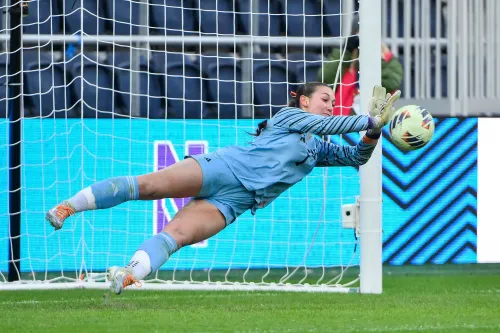 لاعبة كرة القدم ميا هامانت ترتدي زي حارس المرمى، وهي تتصدى لكرة في لحظة حماسية خلال مباراة. خلفها، يظهر الشبك.