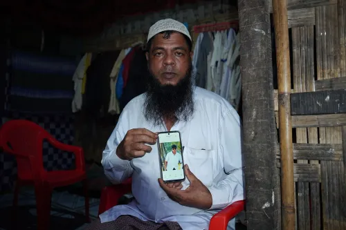 رجل من الروهينغا في مخيم Cox's Bazar يعرض صورة ابنه المختطف، يعكس مأساة الاختطاف والاتجار بالبشر في المخيمات.