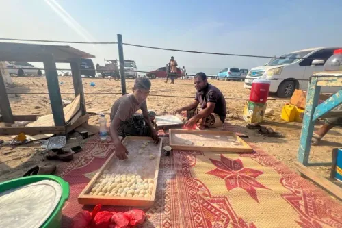 شابان في المكلّا يحضّران خبز البخمري التقليدي على شاطئ البحر خلال موسم البلدة الذي يجذب الزوار ويعزز الاقتصاد المحلي.