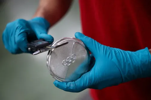 ميدالية فضية أولمبية يتم قياسها بواسطة شخص يرتدي قفازات زرقاء، مع شعار الألعاب الأولمبية مرسومًا عليها، تعكس قيمة الميداليات في الألعاب الشتوية.