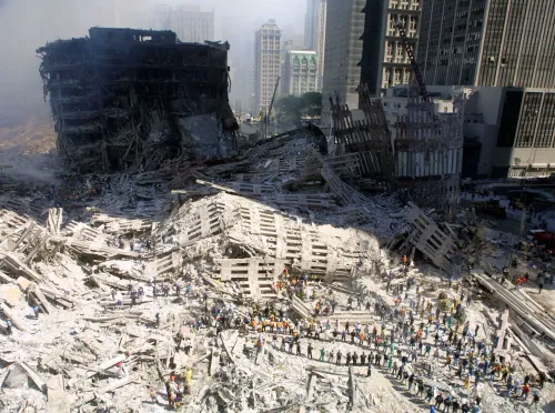ركام موقع مركز التجارة العالمي بعد أحداث 11 سبتمبر 2001 مع فرق الإنقاذ وسط الغبار والدمار، يعكس تداعيات الكارثة الصحية والبيئية طويلة الأمد.