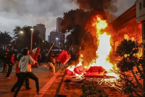 محتجون في إندونيسيا يرمون الحواجز نحو حريق مشتعل في مظاهرة، وسط أجواء مشحونة، مما يعكس تصاعد التوترات في البلاد.