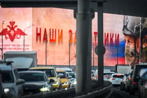 لافتة كبيرة تحمل عبارة "نحن حماة الوطن" على خلفية ملونة، مع حركة مرور كثيفة في الشارع.