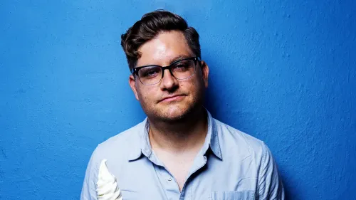 أليكس فالكوني، ممثل كوميدي معروف، يحمل آيس كريم، أمام خلفية زرقاء، يتحدث عن فنون الاحتيال وتقبل الجمهور لها عبر وسائل التواصل.