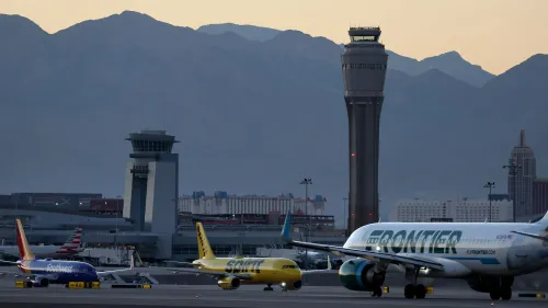 مطار هاري ريد الدولي في لاس فيغاس مع طائرات تجارية على المدرج، خلفه برج المراقبة وجبال في الأفق، يشير إلى مخاطر التصادمات الجوية.