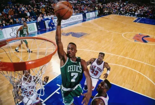 لاعب كرة سلة من فريق بوسطن سيلتيكس يسجل نقطة خلال مباراة ضد نيويورك نيكز، مع وجود لاعبين آخرين في الخلفية.