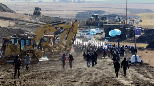 تجمع المتظاهرون في داكوتا الشمالية للاحتجاج على بناء خط أنابيب داكوتا أكسيس، مع وجود آليات ثقيلة في الخلفية.