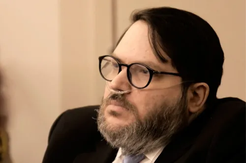 رجل في المحكمة، يرتدي بدلة وربطة عنق، يستخدم أنبوبة أكسجين، ويواجه اتهامات بالاغتصاب في ولاية يوتا.