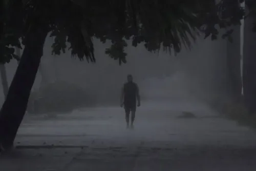 رجل يسير في شارع مبلل أثناء العاصفة الاستوائية ميليسا، مع ظروف جوية سيئة ورؤية منخفضة، مما يعكس تأثيرات العاصفة على المنطقة.