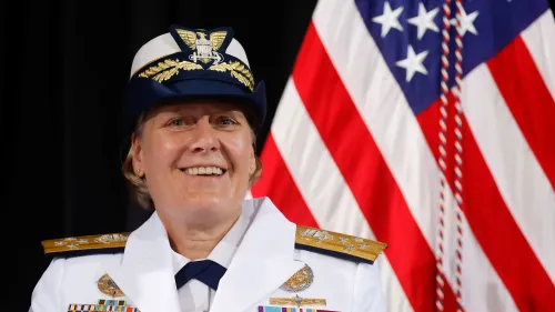 أدميرال ليندا فاغان مبتسمة في زيها الرسمي، مع العلم الأمريكي خلفها، بعد إقالتها من قيادة خفر السواحل بسبب أوجه قصور في القيادة.
