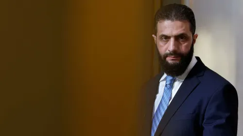 أحمد الشرع، قائد هيئة تحرير الشام، يظهر في مؤتمر صحفي، مع خلفية ضبابية، في سياق التغيرات السياسية في سوريا.