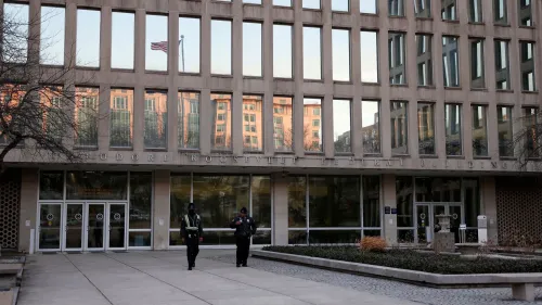 مدخل مبنى ثيودور روزفلت الفيدرالي، يظهر حراس أمن أمامه، مع العلم الأمريكي يرفرف في الخلفية، يعكس التوجهات الجديدة في التوظيف الفيدرالي.