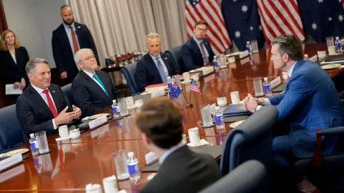 اجتماع لمناقشة اتفاقية "أوكوس" للدفاع، مع وجود مسؤولين أمريكيين وأستراليين، وخلفهم أعلام الولايات المتحدة وأستراليا.