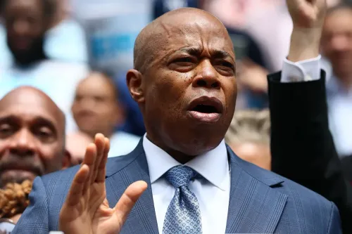 عمدة مدينة نيويورك إريك آدمز يتحدث بجدية خلال حدث عام، مع تعبيرات وجه تعكس القلق بشأن سياسات الملاذ الآمن وتأثيرها على الأمن.