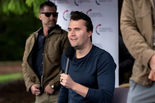 تشارلي كيرك يتحدث في حدث عام، مع وجود حراس شخصيين في الخلفية، حيث يناقش قضايا حرية التعبير.