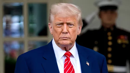 دونالد ترامب يقف أمام البيت الأبيض، مرتديًا بدلة زرقاء وقميصًا أبيض، مع ربطة عنق حمراء، في سياق حديثه عن خفض أسعار الأدوية.