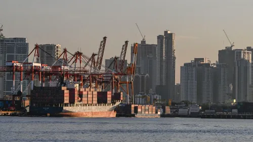 ميناء بحري في الفلبين يظهر سفينة شحن محملة بالحاويات، مع خلفية لمدينة حديثة وأبراج سكنية، في سياق اتفاق تجاري مع الولايات المتحدة.