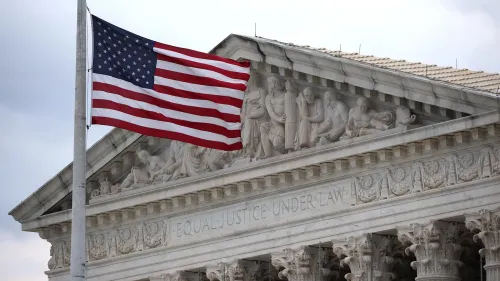 علم الولايات المتحدة يرفرف أمام مبنى المحكمة العليا، حيث تُناقش قضايا تتعلق بسلطة الرئيس على الوكالات المستقلة.