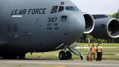 طائرة عسكرية تابعة للقوات الجوية الأمريكية، مع طاقم يعمل على الأرض، في سياق سياسة الهجرة المثيرة للجدل التي تتعلق بترحيل المهاجرين.