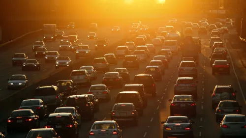 ازدحام مروري على طريق مزدحم تحت أشعة الشمس الغاربة، مما يبرز تأثيرات النقل على أزمة المناخ.