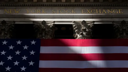 واجهة بورصة نيويورك مع علم الولايات المتحدة، تعكس التوترات الاقتصادية في ظل سياسات ترامب وتأثيرها على الأسواق المالية.
