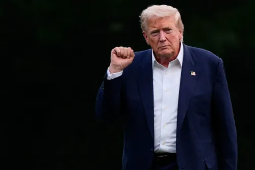 دونالد ترامب يرفع يده بإشارة تحدي، مرتديًا بدلة زرقاء وقميص أبيض، في سياق محادثات تجارية مع الصين والاتحاد الأوروبي.