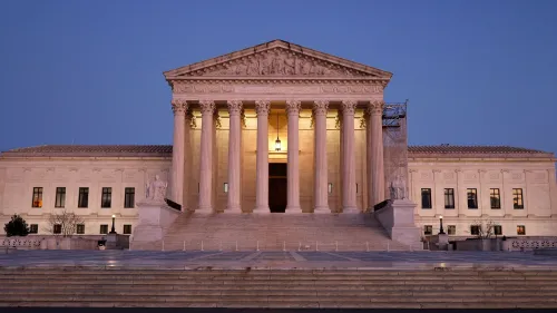 واجهة المحكمة العليا الأمريكية مضاءة في المساء، مع أعمدة ضخمة تعكس أهمية القضايا القانونية المتعلقة بإدارة ترامب.