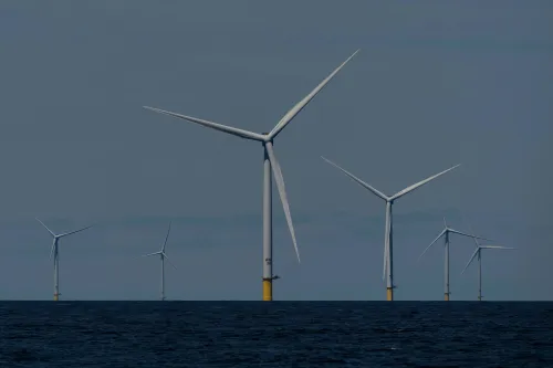 تظهر الصورة مجموعة من توربينات الرياح البحرية في المحيط، مما يعكس جهود الولايات المتحدة في استخدام الطاقة المتجددة لمواجهة ارتفاع أسعار الكهرباء.