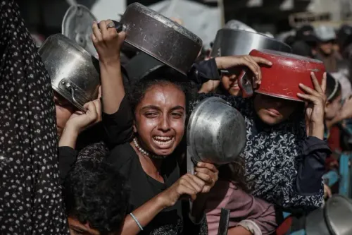 نساء وأطفال فلسطينيون يتجمعون في موقع توزيع المساعدات في غزة، يعبرون عن اليأس والحاجة الماسة للغذاء وسط الأزمات الإنسانية المتزايدة.