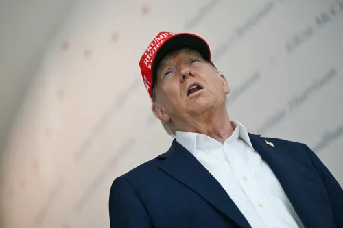 ترامب يتحدث في مناسبة عامة، مرتديًا قبعة تحمل شعار حملته. تعكس تعابير وجهه قلقًا حول قضايا اقتصادية.