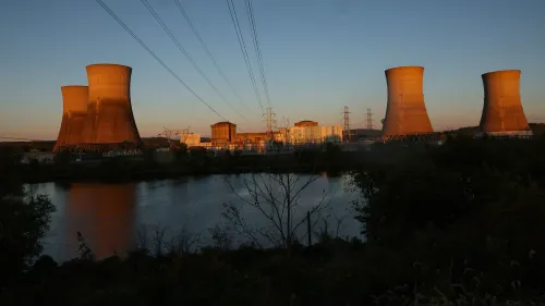 محطة طاقة نووية تظهر أبراج التبريد والمرافق المحيطة بها عند غروب الشمس، تعكس أهمية السلامة النووية والرقابة التنظيمية.