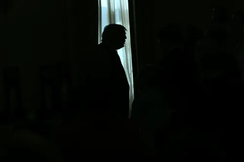 ظل ظلالي لرجل في غرفة مظلمة أمام نافذة مضيئة، تعبير عن التناقضات الأيديولوجية داخل الحزب الجمهوري الأمريكي بين الاشتراكية والدعم الحكومي للأسر.