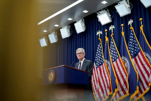 جيروم باول، رئيس مجلس الاحتياطي الفيدرالي، يقف خلف منصة خلال مؤتمر صحفي، مع أعلام الولايات المتحدة خلفه.