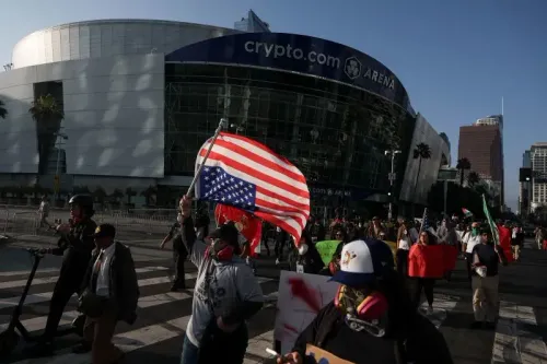 محتجون في لوس أنجلوس يحملون لافتات وأعلام، بما في ذلك علم الولايات المتحدة، أمام ساحة "crypto.com"، في سياق توترات سياسية متزايدة.