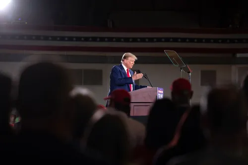 ترامب يتحدث في تجمع انتخابي، محاط بجمهور يرتدي قبعات حمراء، مع العلم الأمريكي في الخلفية، مما يعكس تراجع دعمه بين اللاتينيين.