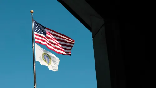 علم الولايات المتحدة يرفرف بجانب علم وزارة الطاقة، مع سماء زرقاء صافية في الخلفية، مما يعكس أهمية الأمن النووي.