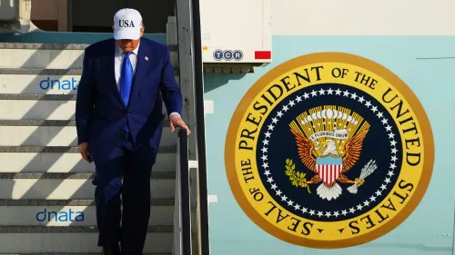 الرئيس الأمريكي دونالد ترامب ينزل من الطائرة، مرتديًا قبعة تحمل شعار "USA"، مع شعار الرئاسة خلفه.