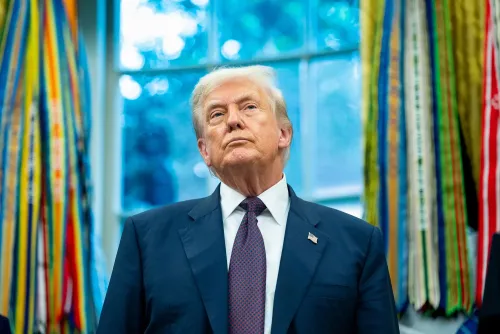 صورة للرئيس الأمريكي دونالد ترامب في المكتب البيضاوي، ينظر إلى الأعلى بتعبير جاد، محاطًا بأشرطة ملونة تعكس تأثيره على النظام التجاري العالمي.