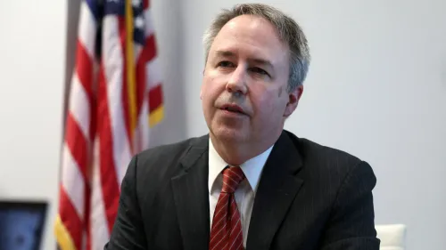 ديفيد هوتيما، المدير المقال لمكتب الأخلاقيات الحكومية، يتحدث في اجتماع، مع العلم الأمريكي خلفه، بعد إقالته من قبل ترامب.