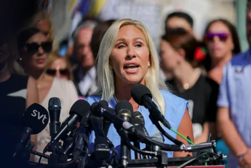 مارجوري تايلور غرين تتحدث أمام حشد من الصحفيين، محاطة بميكروفونات، في سياق جدل سياسي حول دعم ترامب لها.