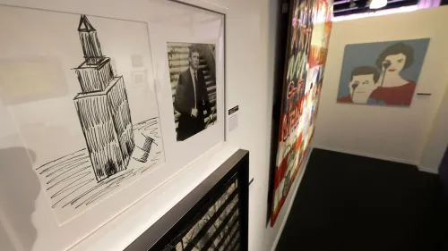 رسمة تخطيطية لمبنى إمباير ستيت بجانب صورة لدونالد ترامب، مع عرض لقطع فنية أخرى في معرض. تعكس الرسومات الجدل حول موهبة ترامب الفنية.