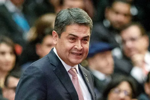 خوان أورلاندو هيرنانديز، الرئيس السابق لهندوراس، مبتسم خلال حدث رسمي، وسط حشد من الحضور.