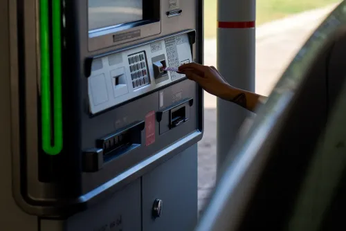 شخص يستخدم جهاز الصراف الآلي لإجراء عملية سحب نقدي، مما يعكس التحديات المتعلقة بالوصول إلى الخدمات المصرفية.
