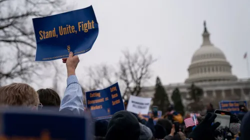 لافتة في مظاهرة أمام مبنى الكابيتول الأمريكي تحمل عبارة "تكاتف، اتحاد، قتال"، مع حشد من المتظاهرين في الخلفية.