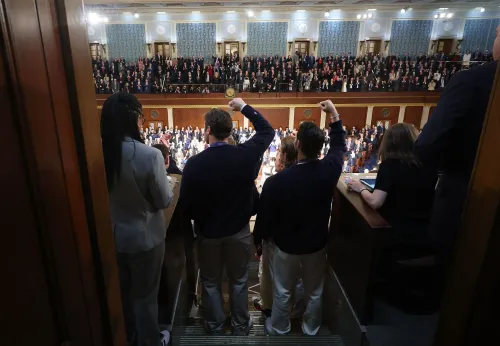 مجموعة من الأشخاص يقفون في قاعة مجلس النواب، يرفعون قبضاتهم في إشارة دعم خلال خطاب حالة الاتحاد للرئيس ترامب.