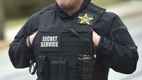 رجل يرتدي سترة واقية تحمل شعار \"الخدمة السرية\"، مع جهاز اتصال، في سياق حماية الرئيس المنتخب دونالد ترامب.