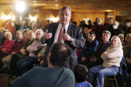 كريس كريستي يتحدث أثناء تجمع جماهيري، محاط بجمهور يستمع بتركيز، وسط أجواء سياسية متوترة.