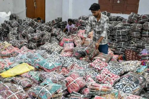 رجل يرتب أكياس الملابس الملونة في مستودع، مما يعكس تأثير الرسوم الجمركية الجديدة على التجارة مع الهند.