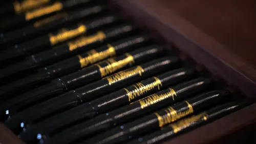 مجموعة من الأقلام السوداء اللامعة مع تفاصيل ذهبية، موضوعة في صندوق خشبي، تعكس الفخامة والاهتمام بالتفاصيل في الأعمال التجارية.